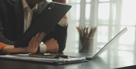 Entrepreneur Asian businessman and businesswoman discussing new business project in tablet in modern Meeting In Modern Office, Asian business casual concept.