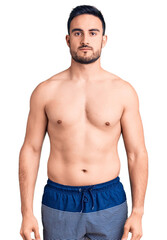 Fototapeta premium Young handsome man wearing swimwear with serious expression on face. simple and natural looking at the camera.