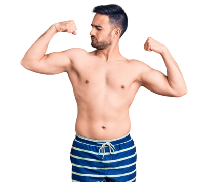 Young handsome man wearing swimwear showing arms muscles smiling proud. fitness concept.