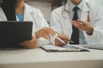medical team having a meeting with doctors in white lab coats and surgical scrubs seated at a table...