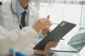 medical team having a meeting with doctors in white lab coats and surgical scrubs seated at a table discussing a patients records,success medical health care, Medicine doctor's working concept