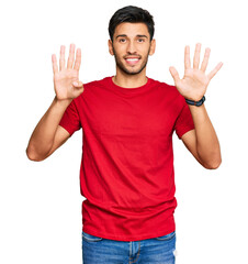 Young handsome man wearing casual red tshirt showing and pointing up with fingers number nine while smiling confident and happy.