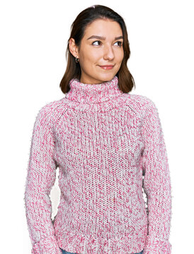 Young caucasian girl wearing wool winter sweater smiling looking to the side and staring away thinking.
