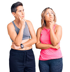 Couple of women wearing sportswear with hand on chin thinking about question, pensive expression. smiling with thoughtful face. doubt concept.