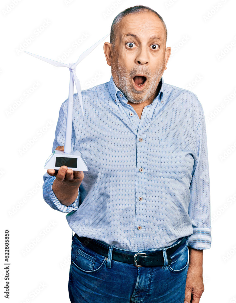 Sticker senior man with grey hair and beard holding solar windmill for renewable electricity scared and amaz