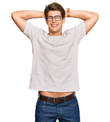 Handsome caucasian man wearing casual clothes and glasses relaxing and stretching, arms and hands behind head and neck smiling happy