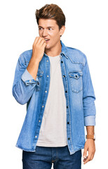 Handsome caucasian man wearing casual denim jacket looking stressed and nervous with hands on mouth biting nails. anxiety problem.
