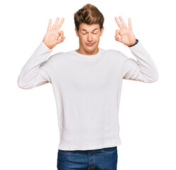 Handsome caucasian man wearing casual white sweater relaxed and smiling with eyes closed doing meditation gesture with fingers. yoga concept.