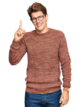 Handsome caucasian man wearing casual sweater and glasses pointing finger up with successful idea. exited and happy. number one.