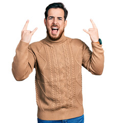 Young hispanic man wearing casual clothes shouting with crazy expression doing rock symbol with hands up. music star. heavy music concept.