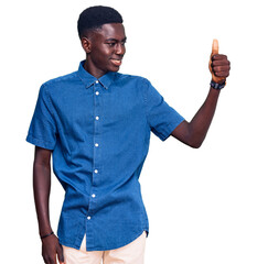 Young african american man wearing casual clothes looking proud, smiling doing thumbs up gesture to the side