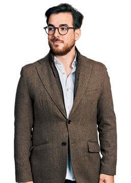 Young hispanic man wearing business jacket and glasses smiling looking to the side and staring away thinking.