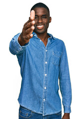 Young african american man wearing casual clothes smiling friendly offering handshake as greeting and welcoming. successful business.