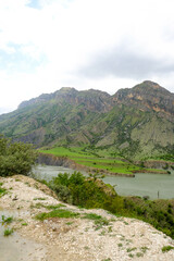 Obraz premium The landscape of the Caucasus Mountains and river on the background of a blue sky with clouds.