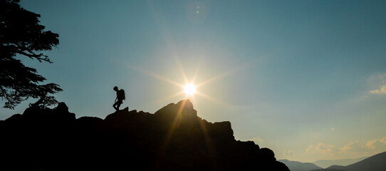 Silhouette of a girl with a backpack walking along a mountain range. climber on top of the mountain. The concept of sports and active life.