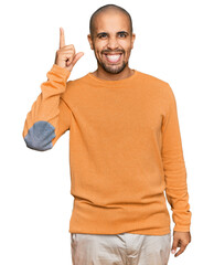 Naklejka premium Hispanic adult man wearing casual winter sweater pointing finger up with successful idea. exited and happy. number one.