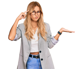 Beautiful blonde young woman wearing business clothes confused and annoyed with open palm showing copy space and pointing finger to forehead. think about it.
