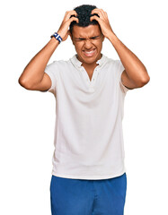 Young arab man wearing casual clothes suffering from headache desperate and stressed because pain and migraine. hands on head.