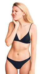 Naklejka premium Young beautiful blonde woman wearing bikini touching mouth with hand with painful expression because of toothache or dental illness on teeth. dentist