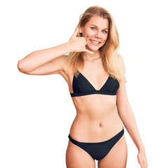 Young beautiful blonde woman wearing bikini smiling doing phone gesture with hand and fingers like talking on the telephone. communicating concepts.