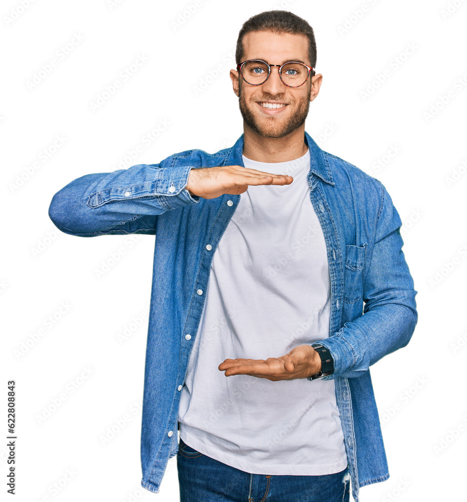 Poster young caucasian man wearing casual clothes gesturing with hands showing big and large size sign, mea