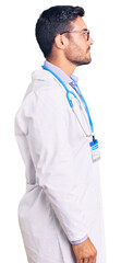 Young hispanic man wearing doctor uniform and stethoscope looking to side, relax profile pose with natural face and confident smile.