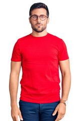 Fototapeta premium Young hispanic man wearing casual clothes and glasses with serious expression on face. simple and natural looking at the camera.