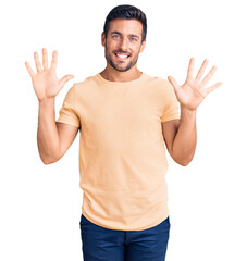 Naklejka premium Young hispanic man wearing casual clothes showing and pointing up with fingers number ten while smiling confident and happy.