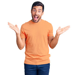 Fototapeta premium Young hispanic man wearing casual clothes celebrating victory with happy smile and winner expression with raised hands