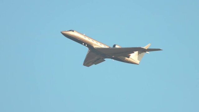 Generic Golden VIP Executive Business Jet with No Markings Flying into a Blue Sky After Taking Off on a Sunny Day