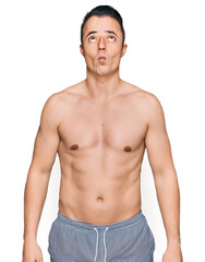 Fototapeta premium Handsome young man wearing swimwear shirtless making fish face with lips, crazy and comical gesture. funny expression.