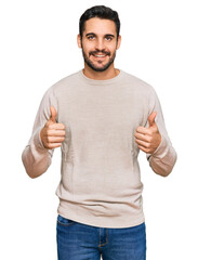 Fototapeta premium Young hispanic man wearing casual clothes success sign doing positive gesture with hand, thumbs up smiling and happy. cheerful expression and winner gesture.