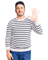 Naklejka premium Young hispanic man wearing casual clothes showing and pointing up with fingers number five while smiling confident and happy.