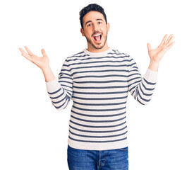 Naklejka premium Young hispanic man wearing casual clothes celebrating crazy and amazed for success with arms raised and open eyes screaming excited. winner concept