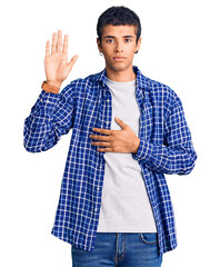 Young african amercian man wearing casual clothes swearing with hand on chest and open palm, making...