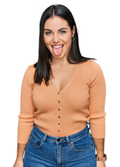 Young hispanic woman wearing casual clothes sticking tongue out happy with funny expression. emotion concept.