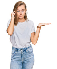 Beautiful young blonde woman wearing casual white t shirt confused and annoyed with open palm...
