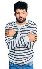 Young arab man with beard wearing casual striped sweater shaking and freezing for winter cold with sad and shock expression on face