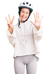 Beautiful brunette young woman wearing bike helmet and sporty clothes showing and pointing up with fingers number eight while smiling confident and happy.