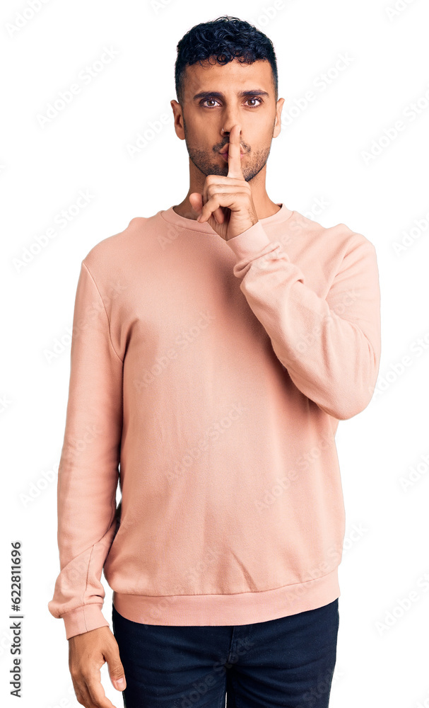 Poster Young hispanic man wearing casual clothes asking to be quiet with finger on lips. silence and secret concept.