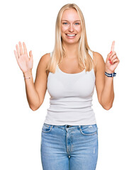 Young blonde girl wearing casual style with sleeveless shirt showing and pointing up with fingers...