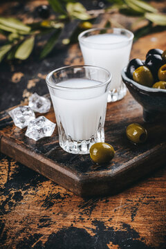 Traditional greek vodka ouzo and marinated olives on rustic wooden table