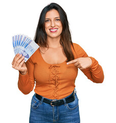 Beautiful hispanic woman holding 1000 south korean won banknotes pointing finger to one self smiling happy and proud