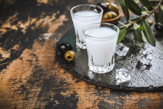 Traditional greek vodka ouzo and marinated olives on rustic wooden table