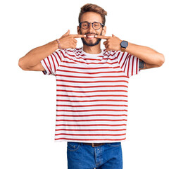 Fototapeta premium Handsome blond man with beard wearing casual clothes and glasses smiling cheerful showing and pointing with fingers teeth and mouth. dental health concept.