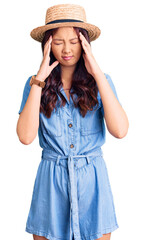 Fototapeta premium Young beautiful chinese girl wearing summer hat with hand on head, headache because stress. suffering migraine.