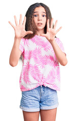 Fototapeta na wymiar Cute hispanic child girl wearing casual clothes afraid and terrified with fear expression stop gesture with hands, shouting in shock. panic concept.