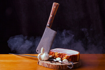 Fototapeta na wymiar Bacon with meat with knife on the wooden cutting board with black background