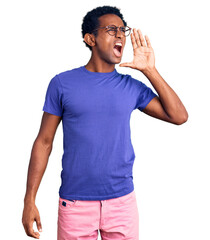 African handsome man wearing casual clothes and glasses shouting and screaming loud to side with hand on mouth. communication concept.