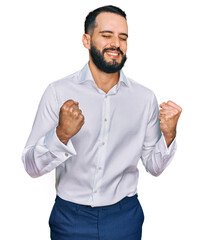 Young man with beard wearing business shirt excited for success with arms raised and eyes closed celebrating victory smiling. winner concept.
